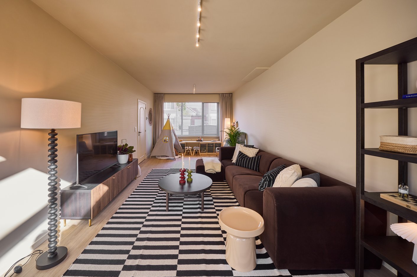 Woonkamer met bruine bank en zwart wit kleed