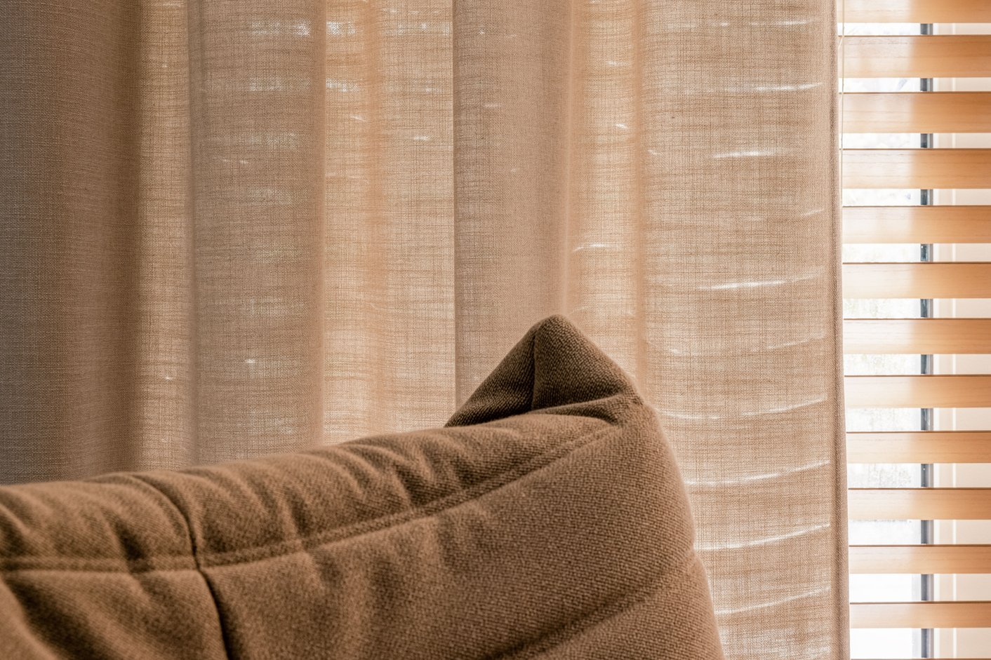 Houtkleurige jaloezieën met een zandkleurig inbetween gordijn