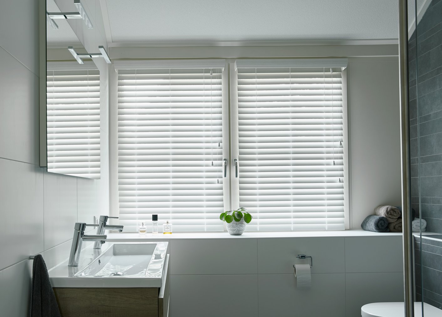 Witte jaloezieën in badkamer