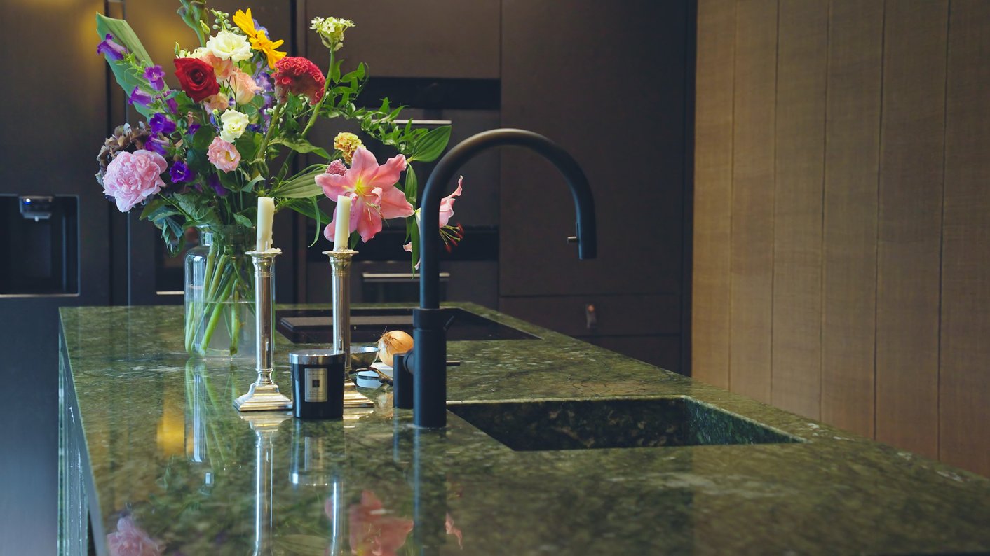 Zwarte keuken met groen aanrechtblad en prachtige bos bloemen